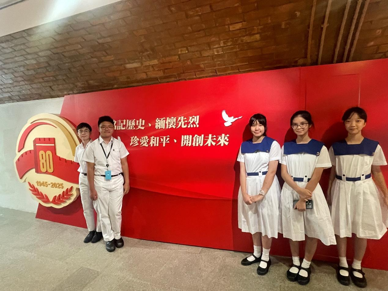 A group of people standing in front of a red signDescription automatically generated